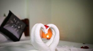 A bed with a heart-shaped towel arrangement and a candle. - Rice Village Homestay (Da Nang)