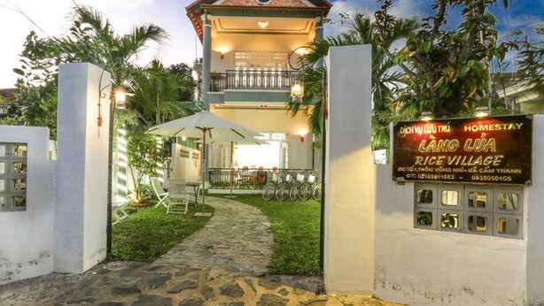 A two-story building with a covered patio area, a signboard for a rice village, and a bicycle parking area. - Rice Village Homestay (Da Nang)