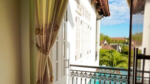 A balcony with a view of a garden and neighboring buildings. - Rice Village Homestay (Da Nang)