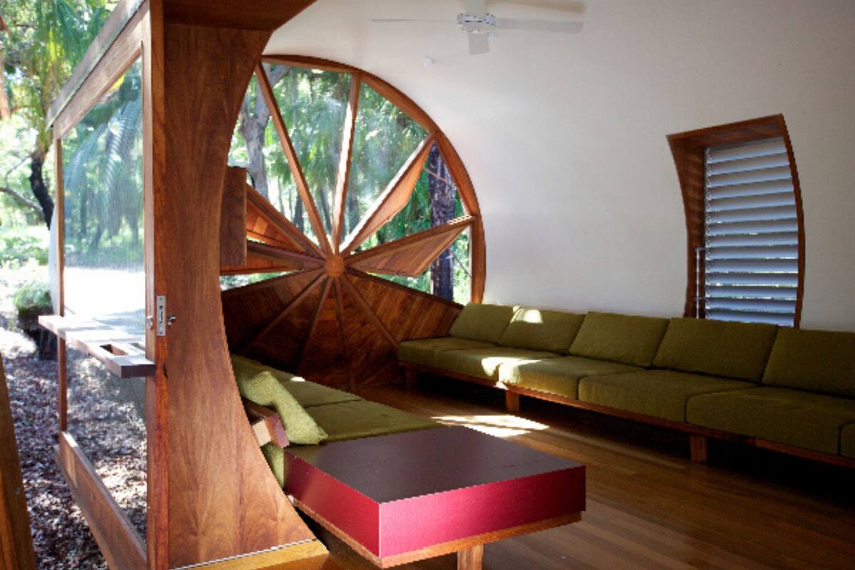 Ein Zimmer mit einer runden Holzkonstruktion, einem grünen Sofa und einem roten Tisch.