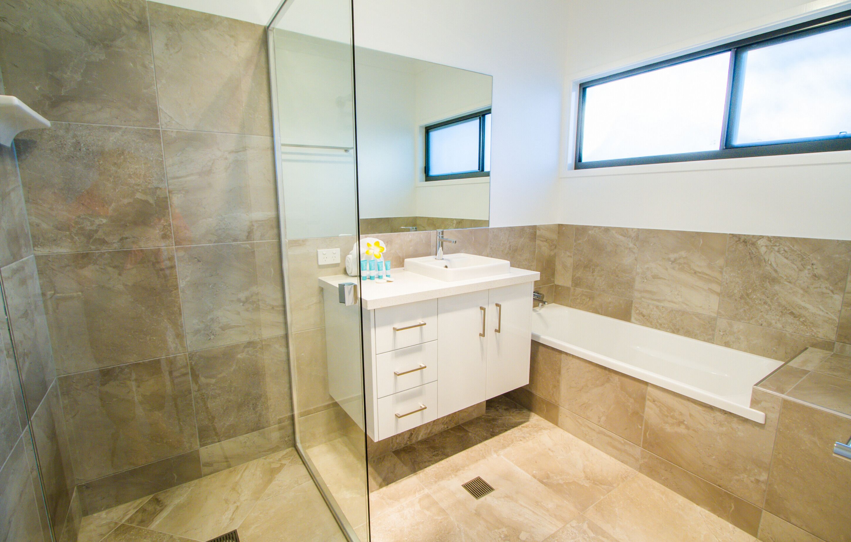 A modern bathroom with a glass shower enclosure, a white sink, and a bathtub.