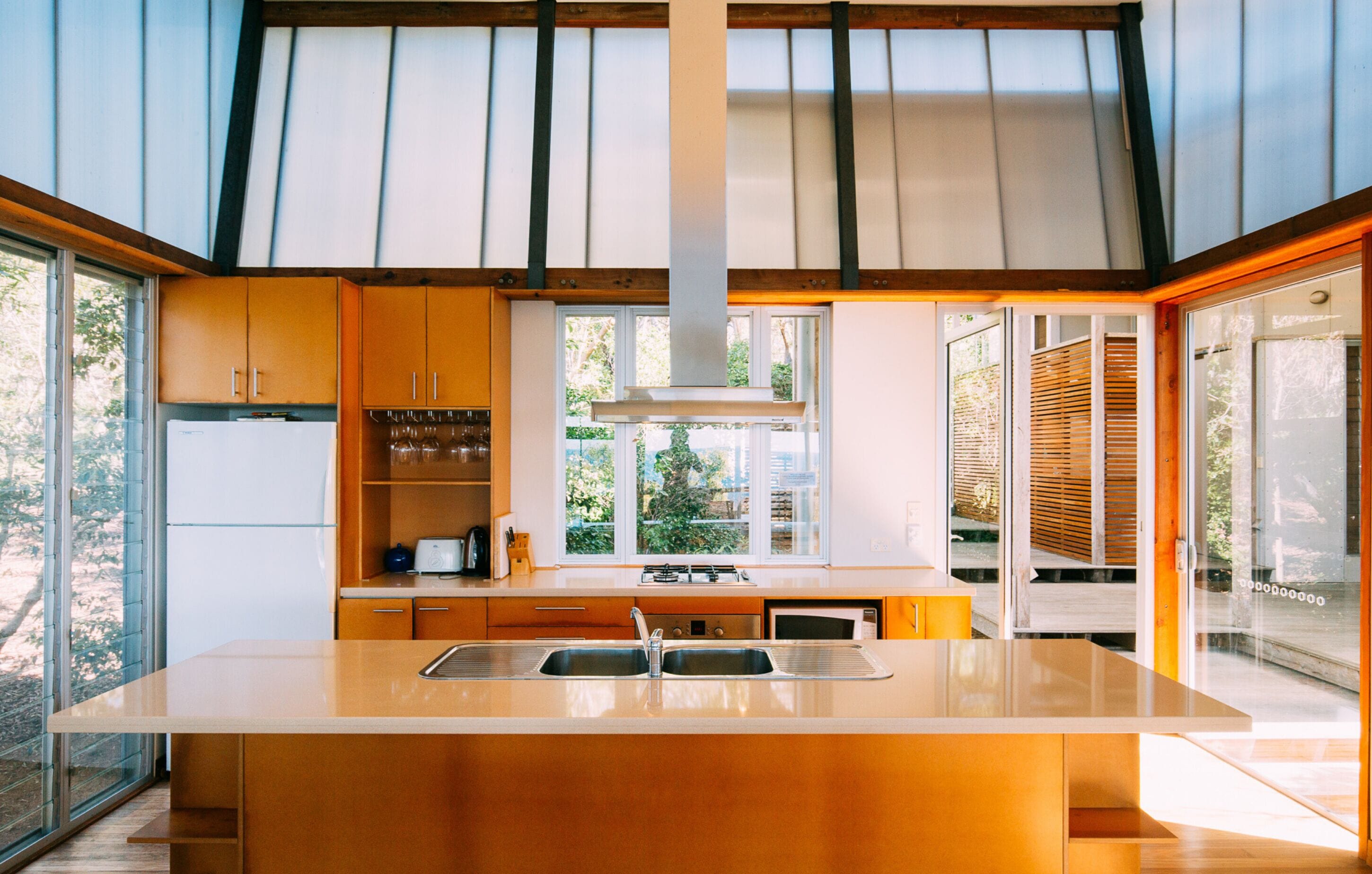 A modern kitchen with a central island, built-in appliances, and large windows offering views of the outdoors.