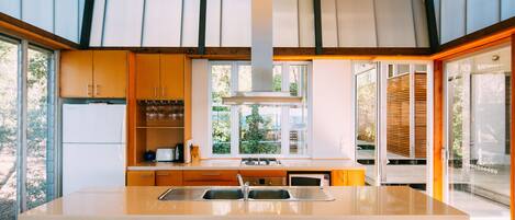 A modern kitchen with a central island, built-in appliances, and large windows offering views of the outdoors.