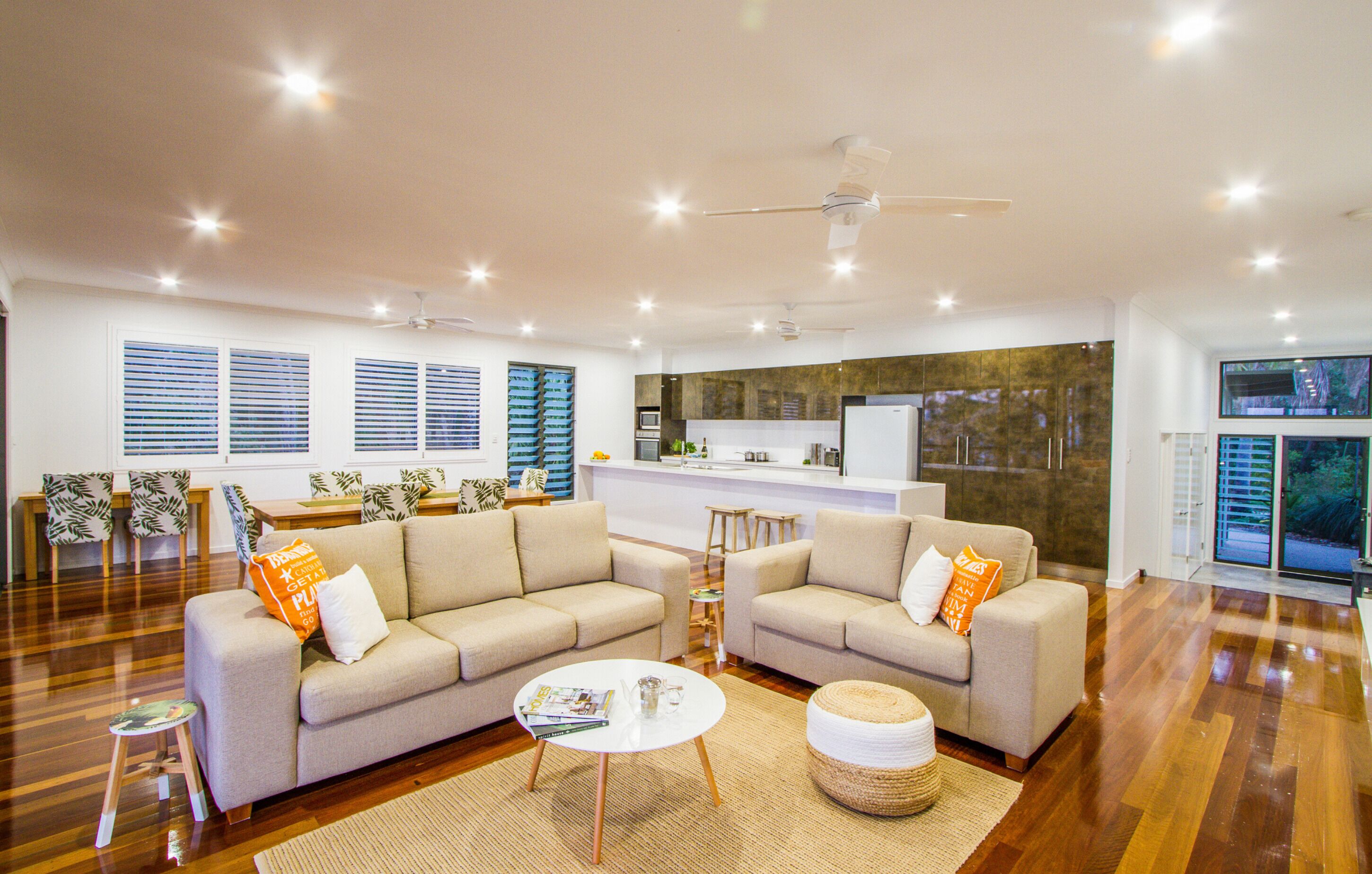 A spacious living room with two sofas, a coffee table, and a dining area with chairs and a kitchen in the background.