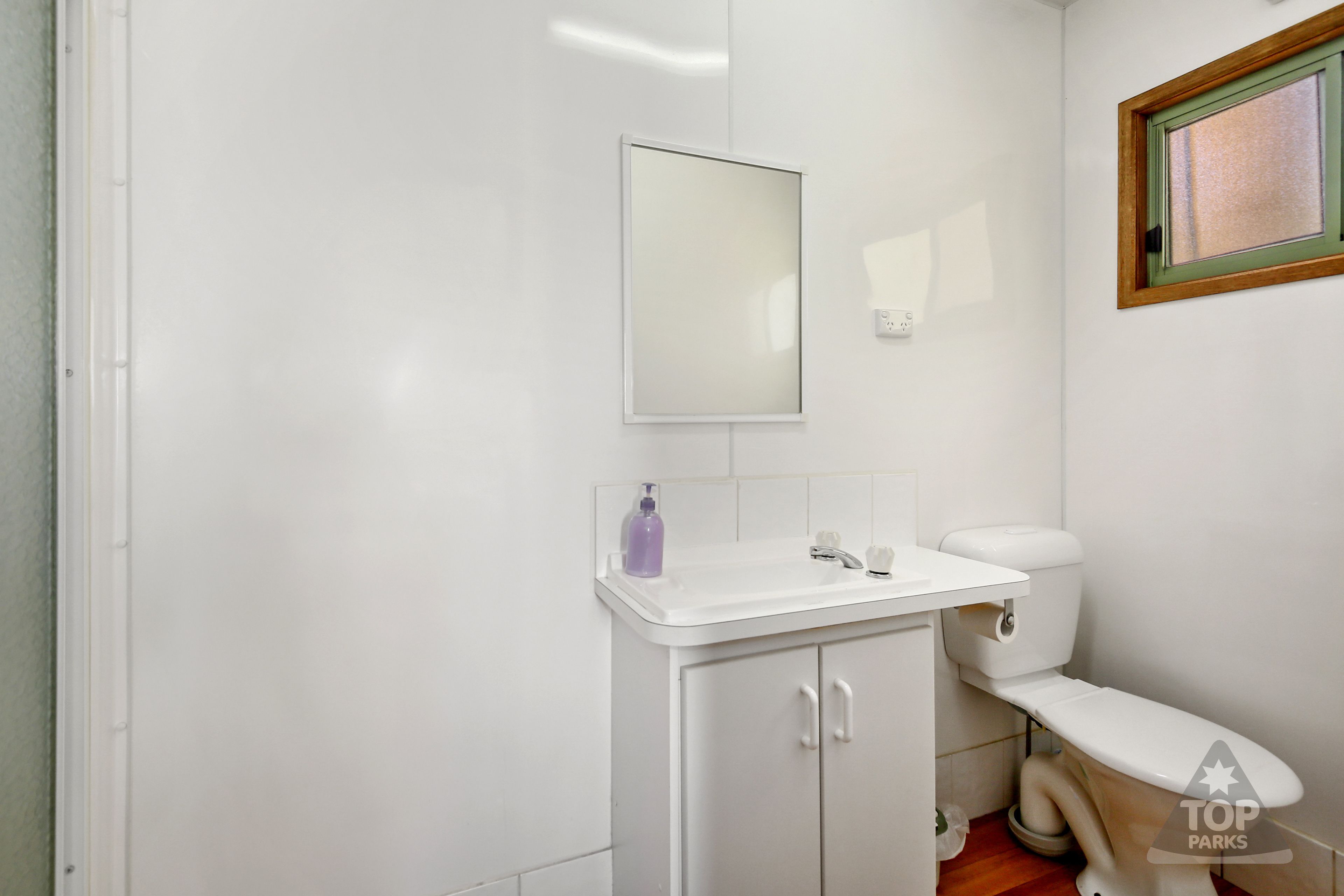 A small, white bathroom with a toilet, a sink, and a mirror.