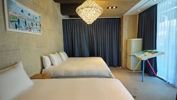 Habitación de hotel con una cama grande, una mesita con un libro, un refrigerador y una araña.