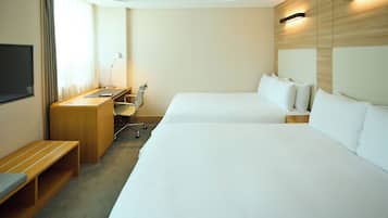 A hotel room with two beds, a desk, a chair, a TV, and a window with curtains.
