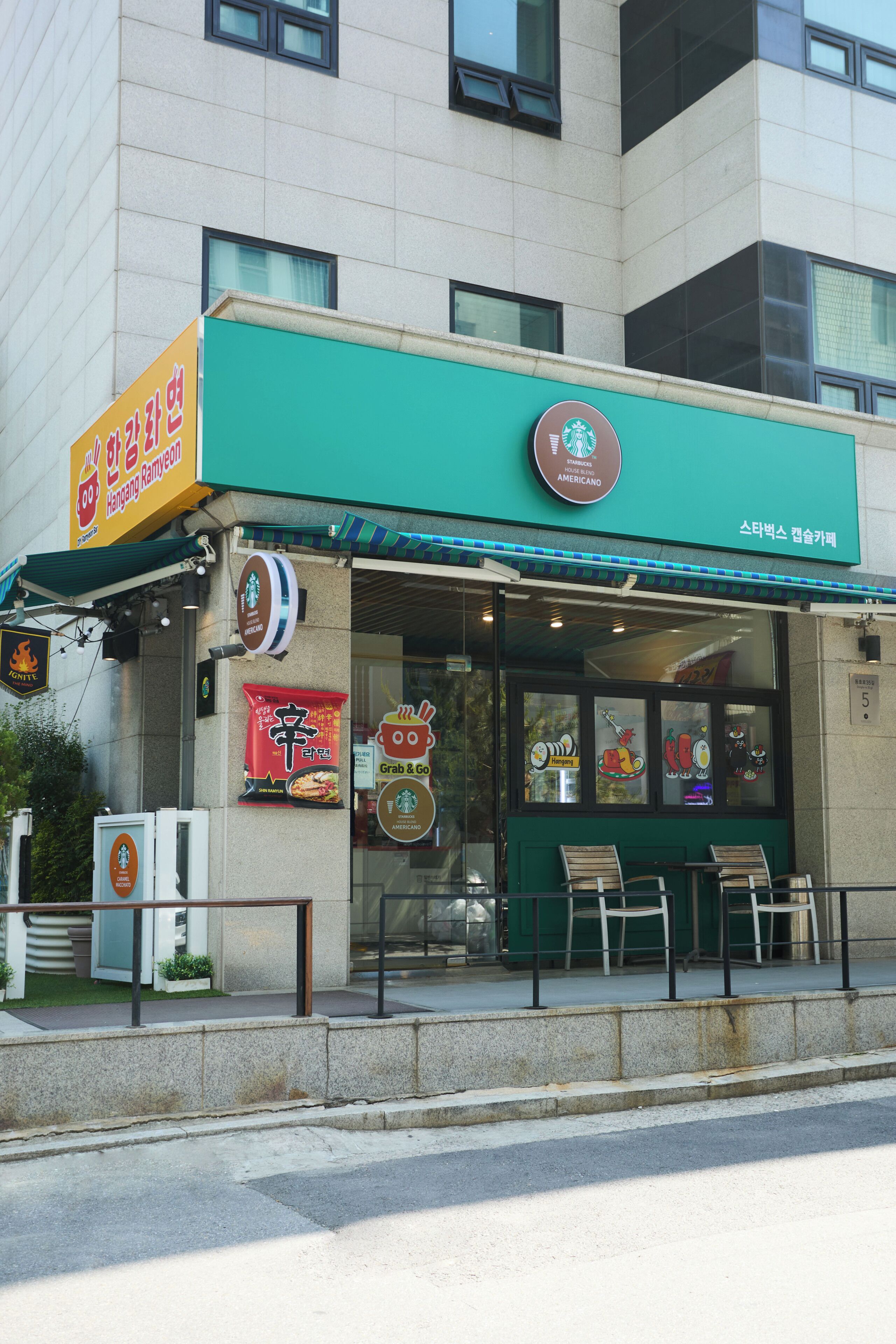 Un escaparate con toldo verde, logotipo de Starbucks y anuncio de restaurante.