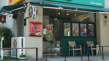 Un escaparate con toldo verde, logotipo de Starbucks y anuncio de restaurante.
