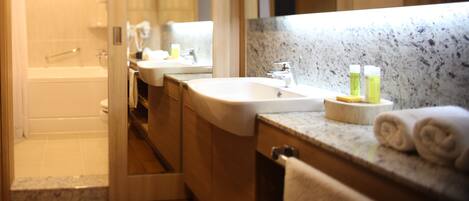 A modern bathroom with a bathtub, two sinks, and a large mirror.