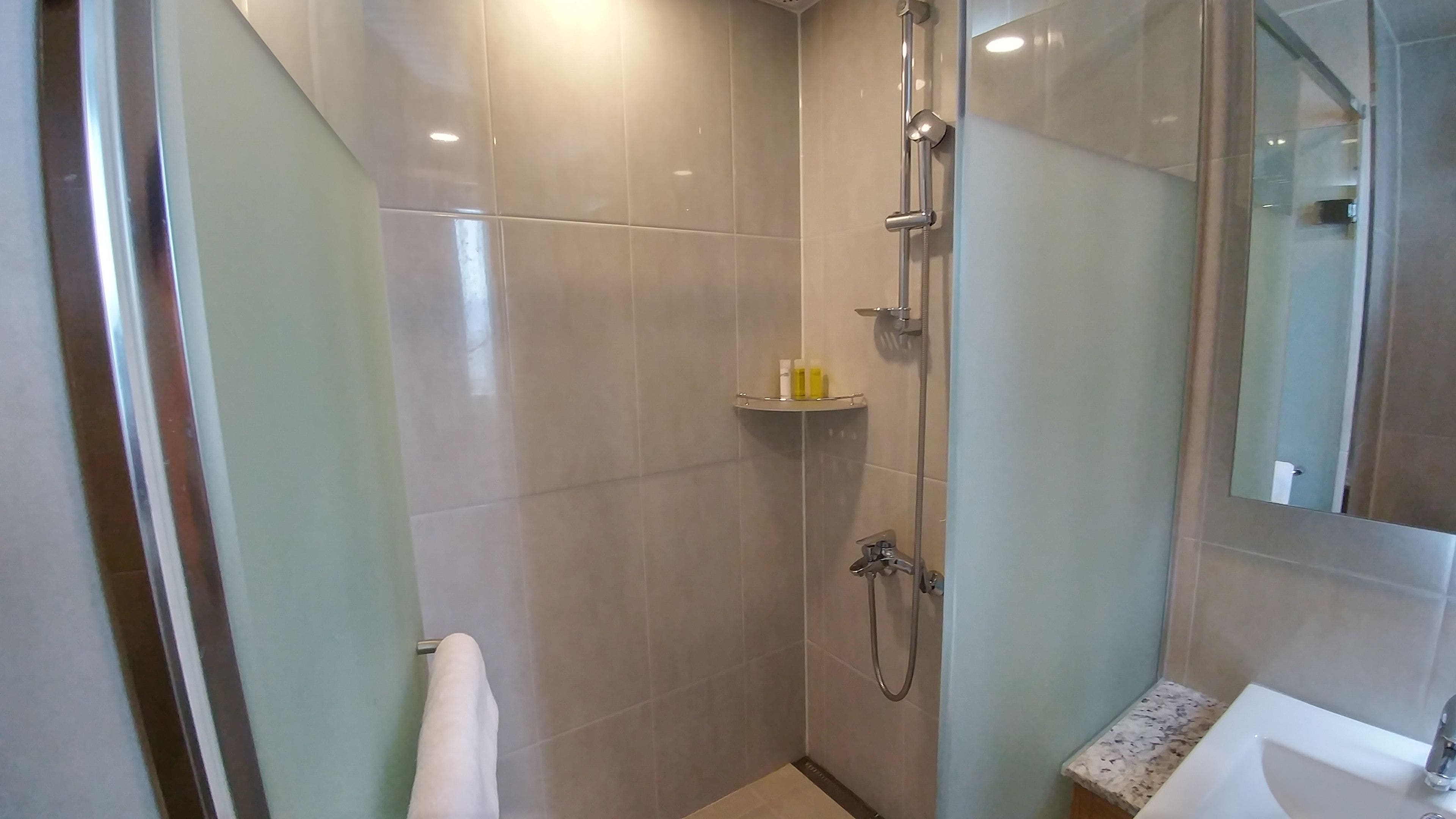 Une salle de bain moderne avec une douche à parois de verre, des toilettes et un lavabo avec un miroir.