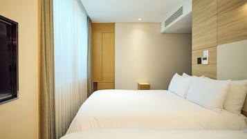 Habitació d'hotel amb un llit gran, una taula de nit, un panell de control fixat a la paret i una finestra amb cortines.