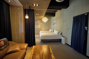 A modern hotel room with a large bed, a wooden coffee table, a leather sofa, and a chandelier. - Acube Hotel (Seoul)