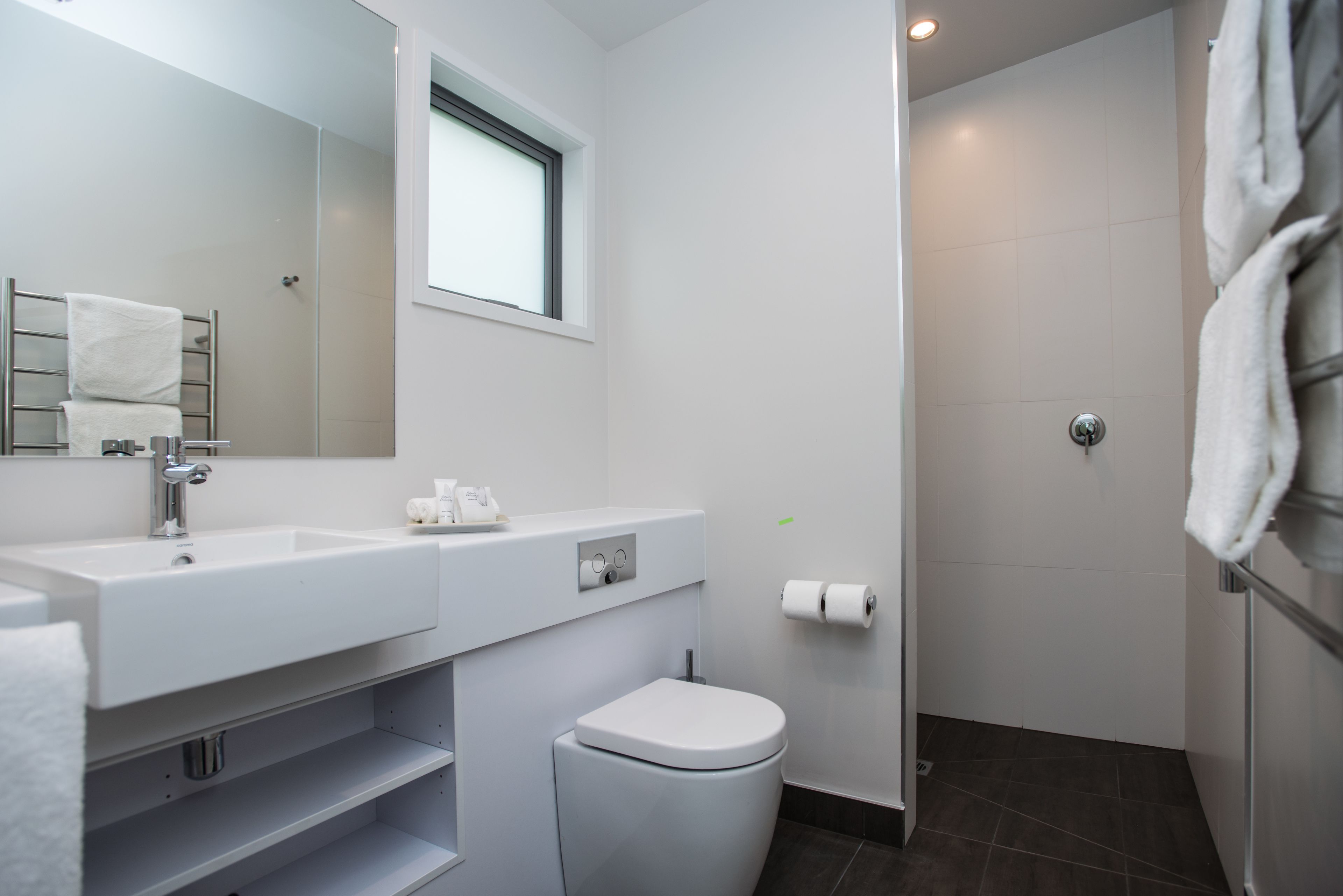 Un baño moderno con lavamanos, inodoro y ducha.