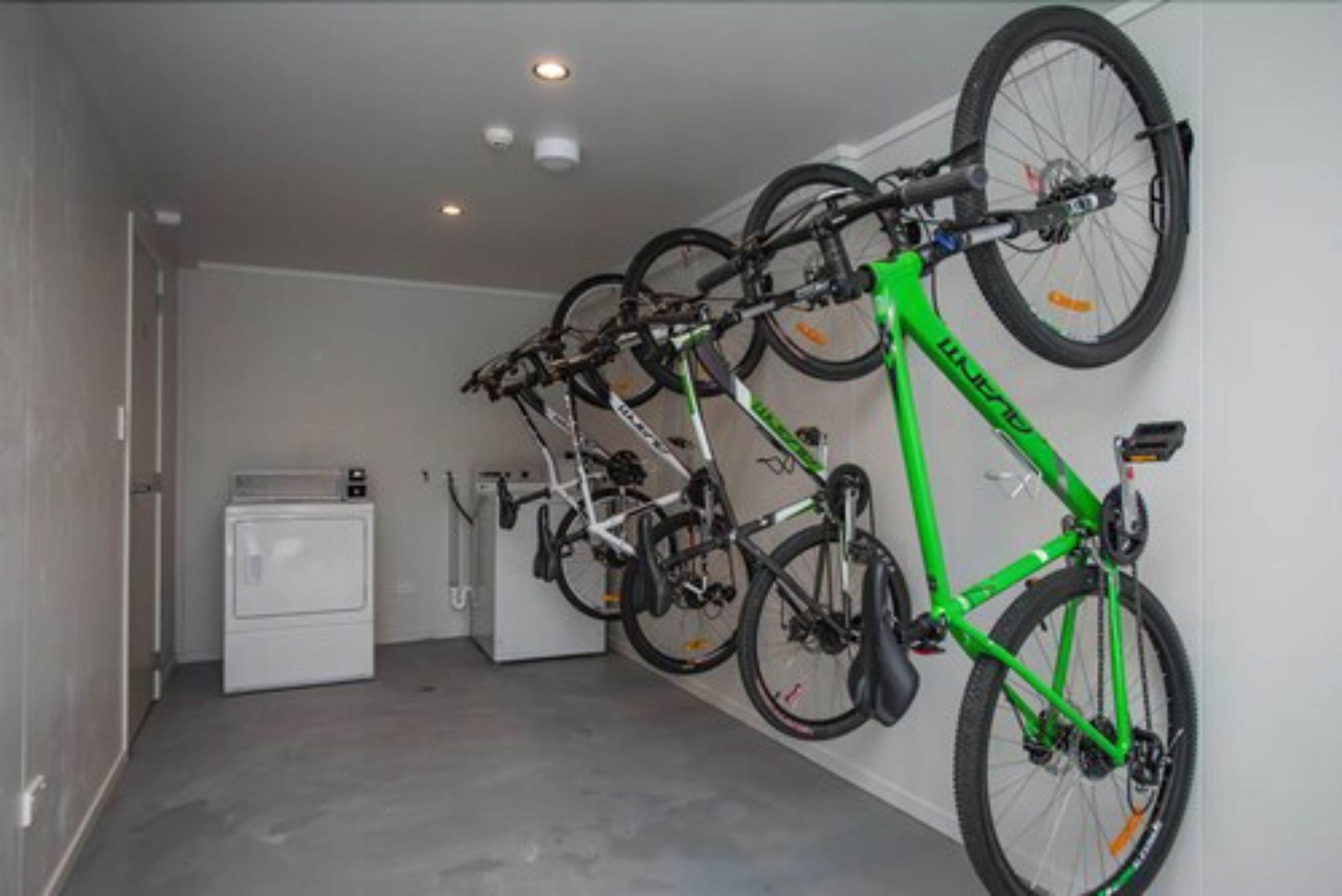 Una habitación con un aparcavesisletas que contiene varias bicicletas, una lavadora y una secadora.