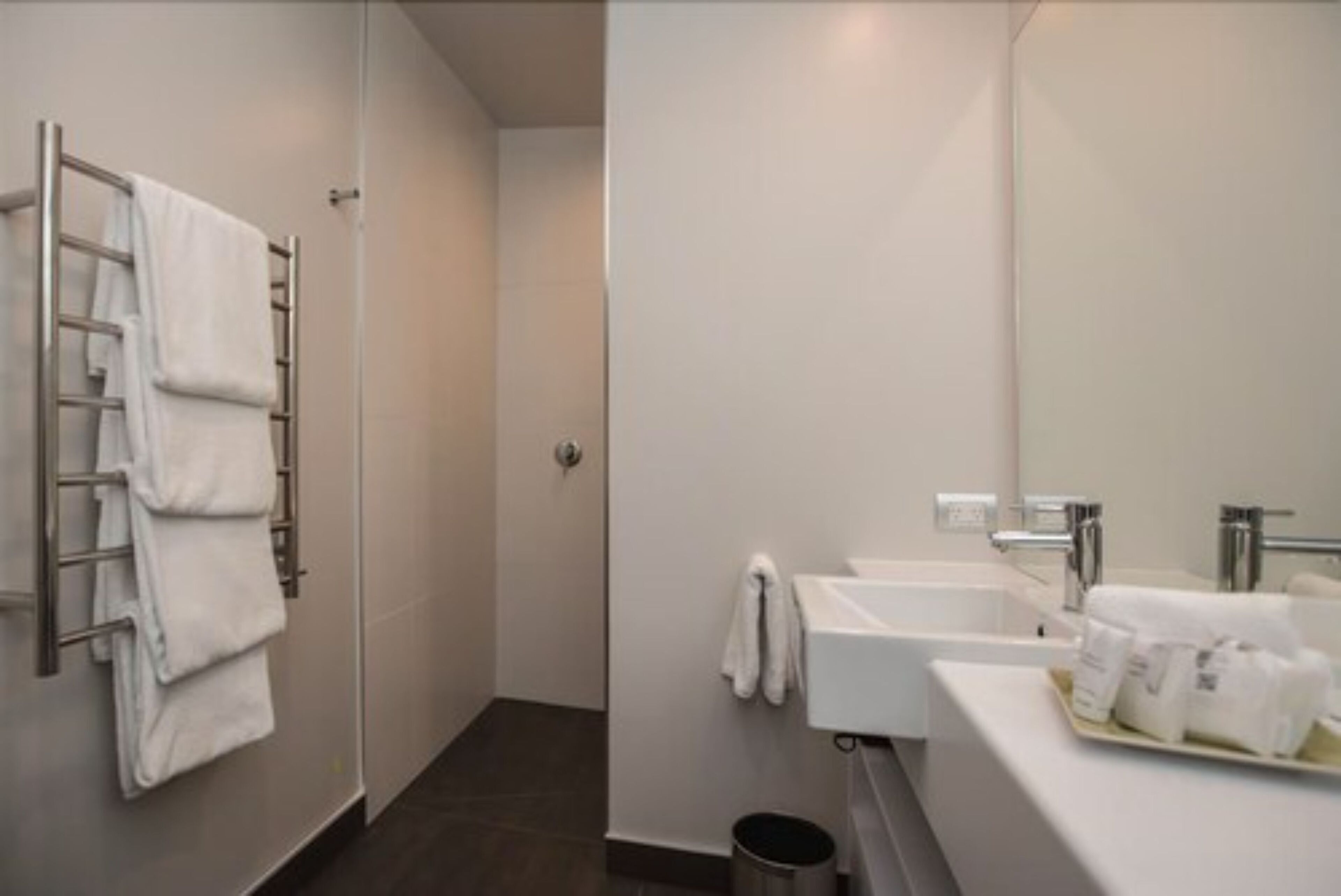 Un bany modern amb plat de dutxa, penjador de tovalloles i un lavabo amb mirall.