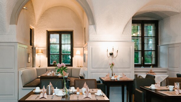 A dining area with tables set for service, arched ceilings, and a view of the outdoors. - Hotel Schloss Lehen (Bad Friedrichshall)