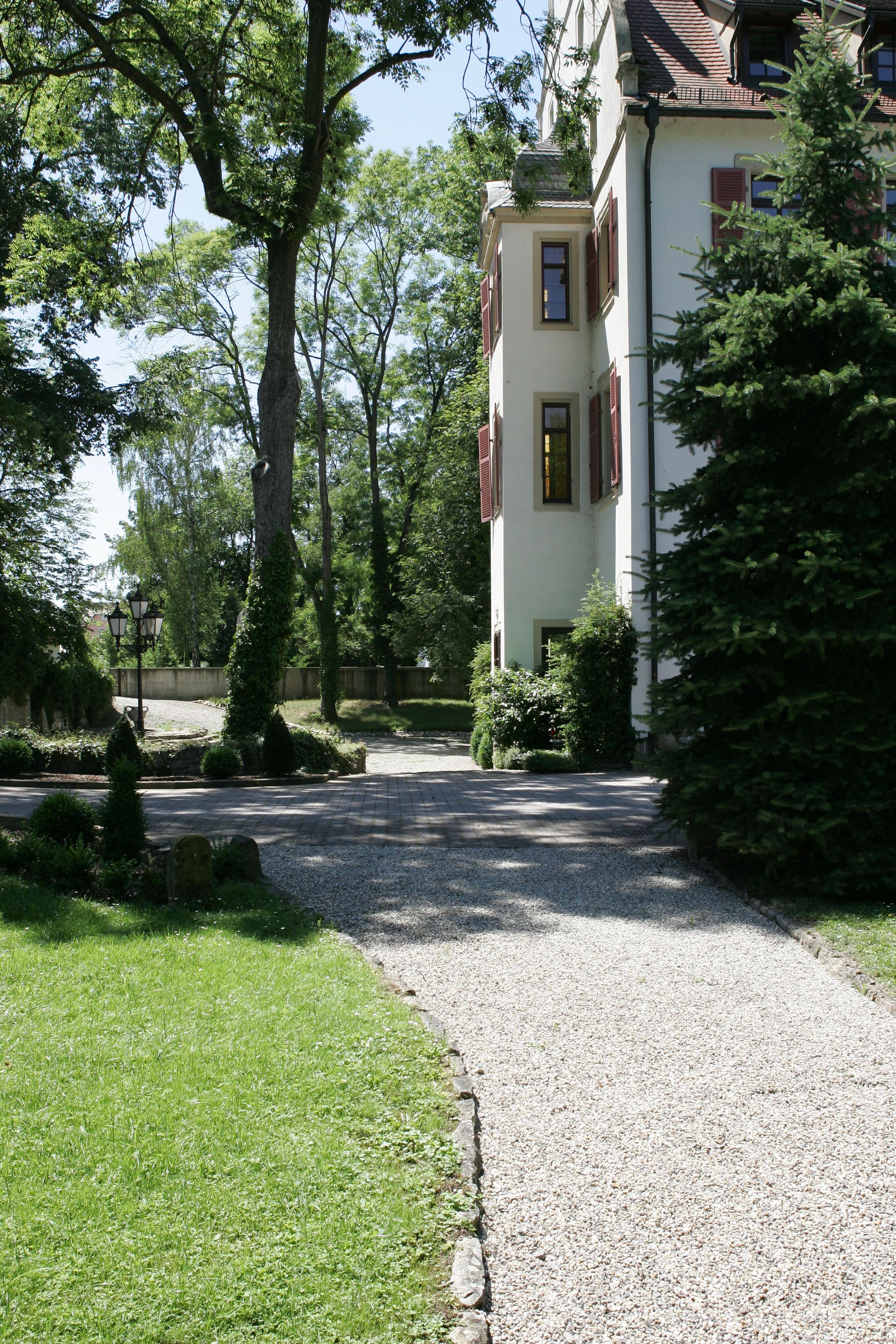 A pathway leading to a building with a traditional architectural style, surrounded by lush greenery and trees.