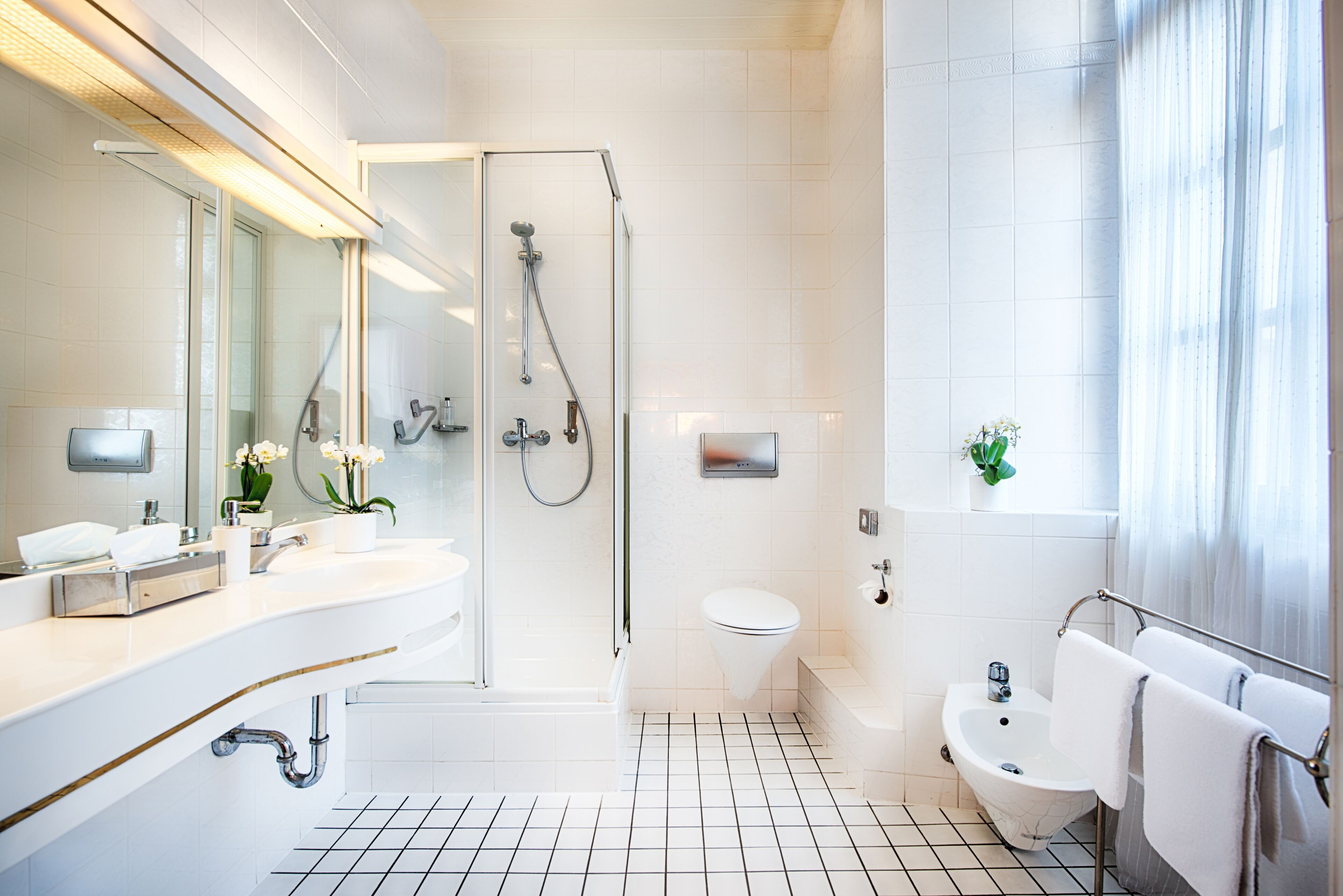 A modern bathroom with a shower, toilet, sink, and bidet.