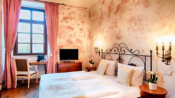 A bedroom with a bed, a desk, a television, and a wall-mounted light fixture.