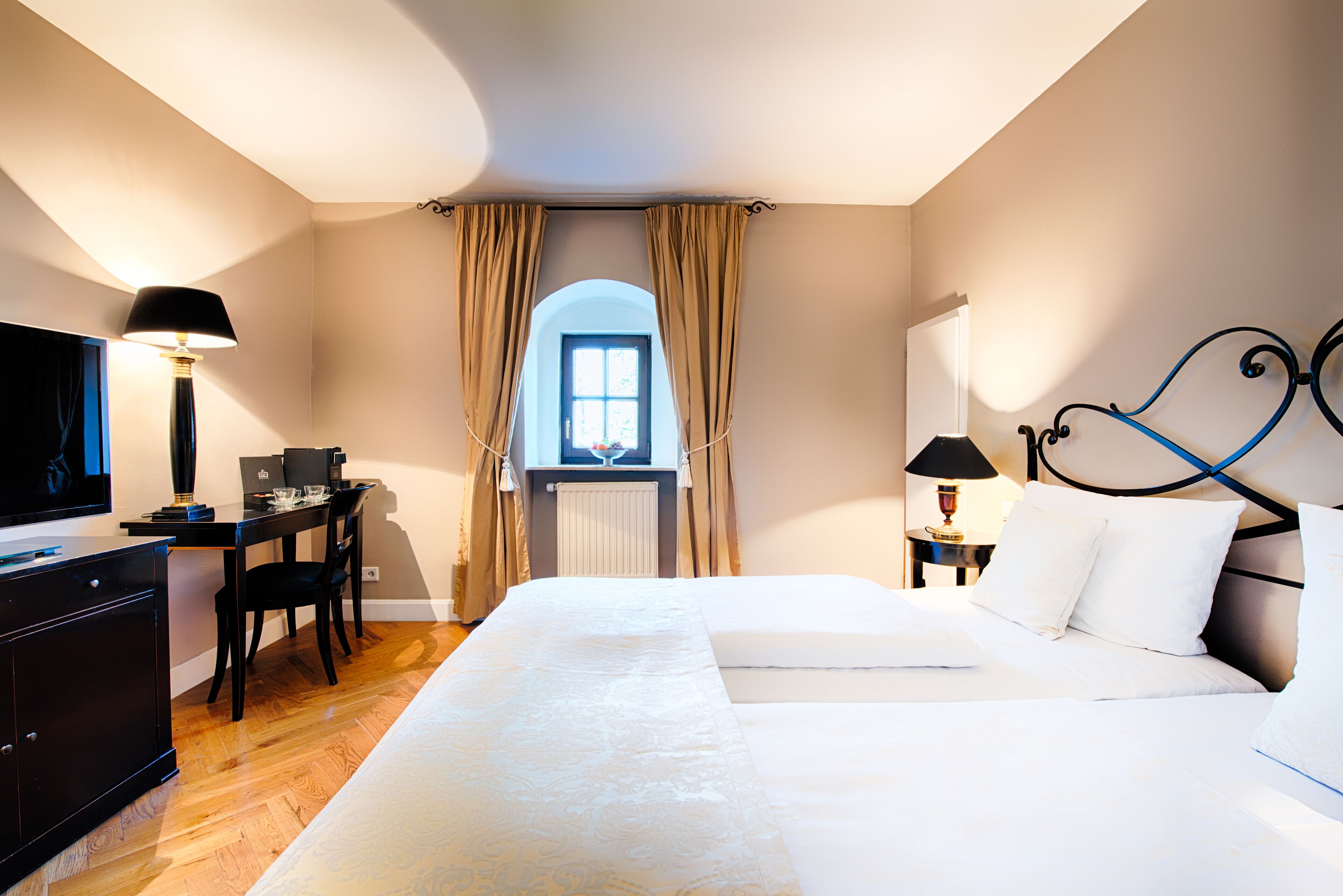 A hotel room with a bed, desk, and television.