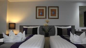 A hotel room with two beds, a nightstand, a lamp, and two framed pictures on the wall.