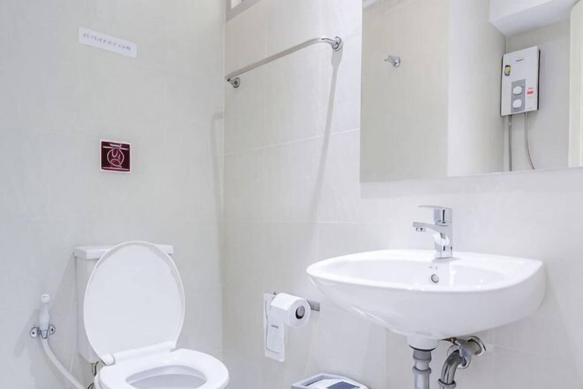 A bathroom with a toilet, sink, and hand dryer.