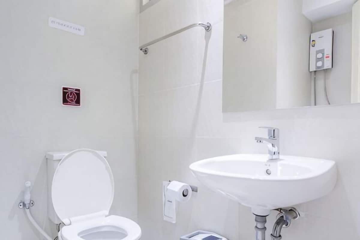 Un baño con inodoro, lavamanos y secamanos.