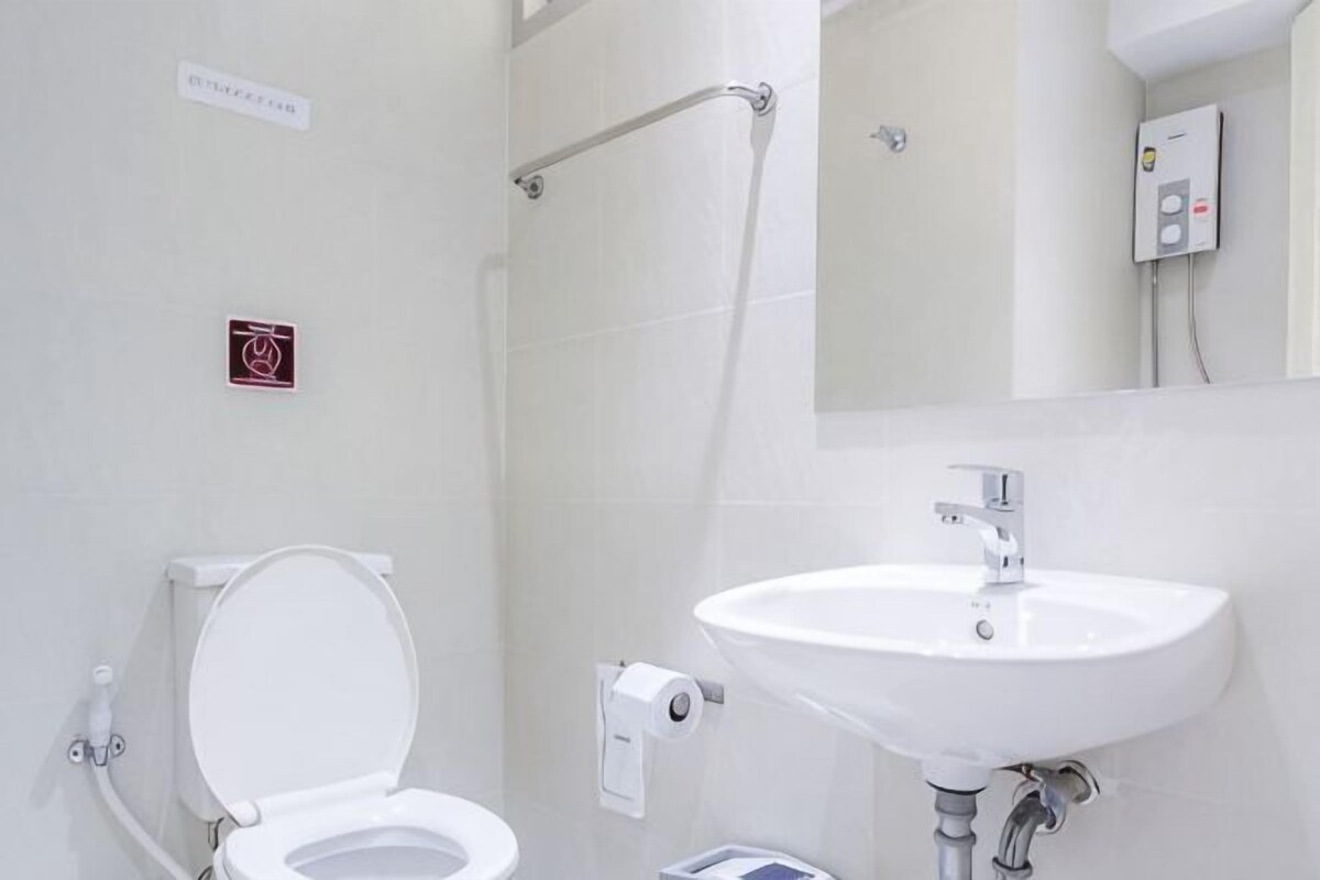 A bathroom with a toilet, sink, and hand dryer.