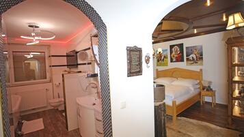 A bedroom with a wooden bed, a nightstand, a lamp, and a wall with framed pictures.
