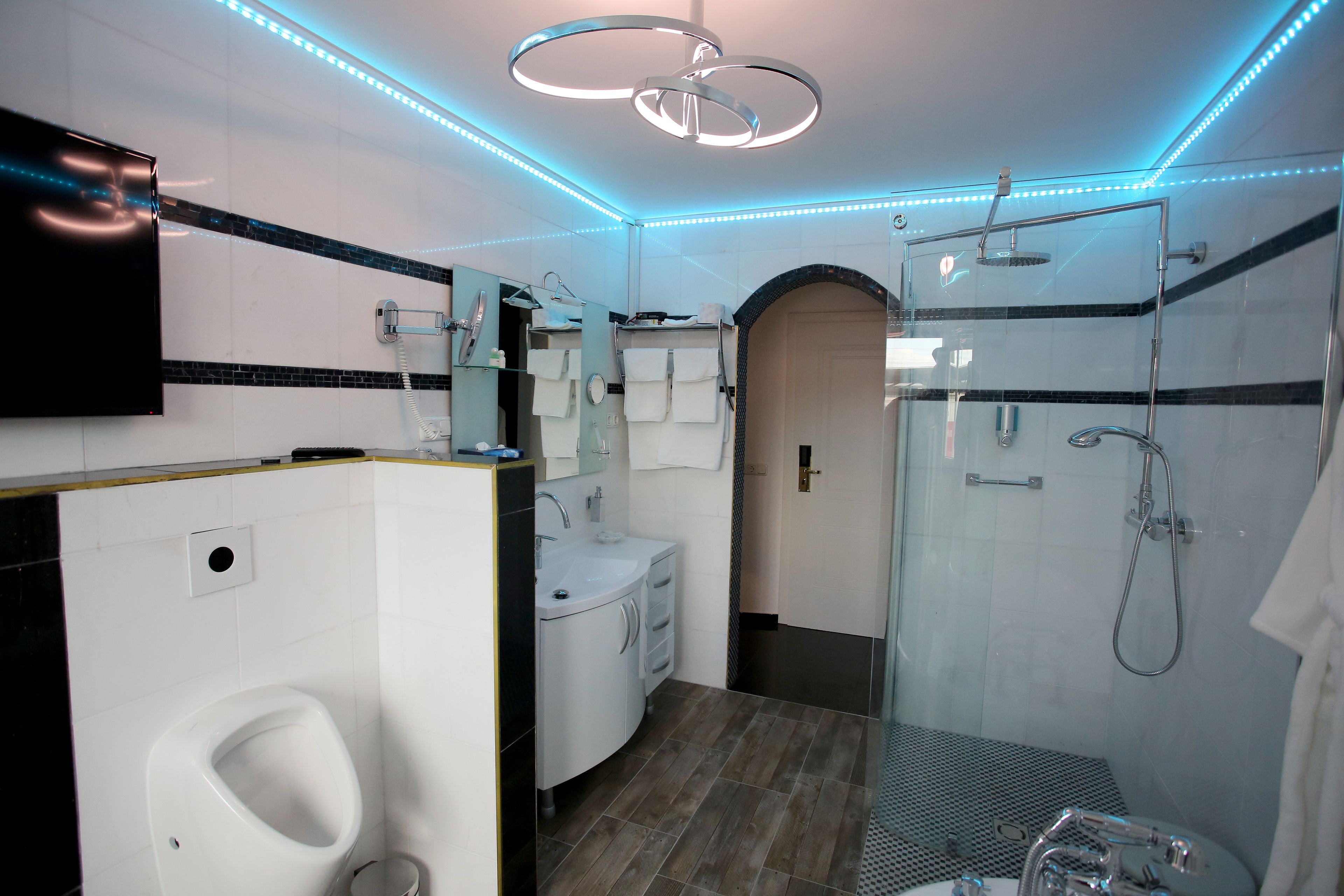 Une salle de bain moderne avec une douche en verre, un lavabo blanc avec un miroir et un urinoir.