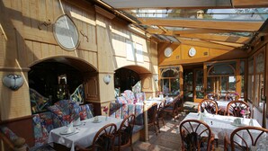 Un restaurant aux murs en bois, aux bancs à motifs et aux tables dressées pour le repas.