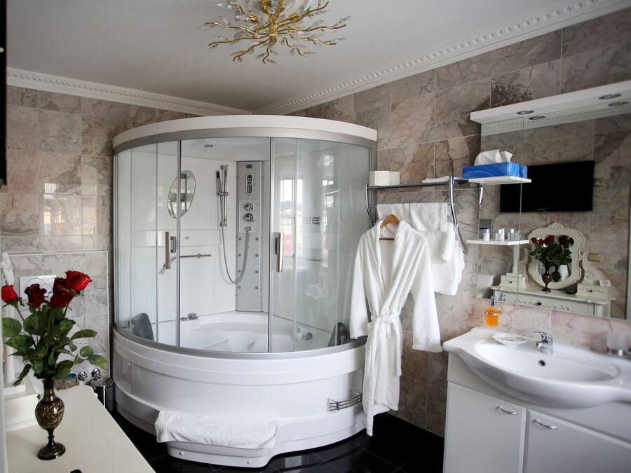 Ein modernes Badezimmer mit einer einteiligen Duschkabine, einer weißen Badewanne, einem Waschtisch und einem Spiegel.