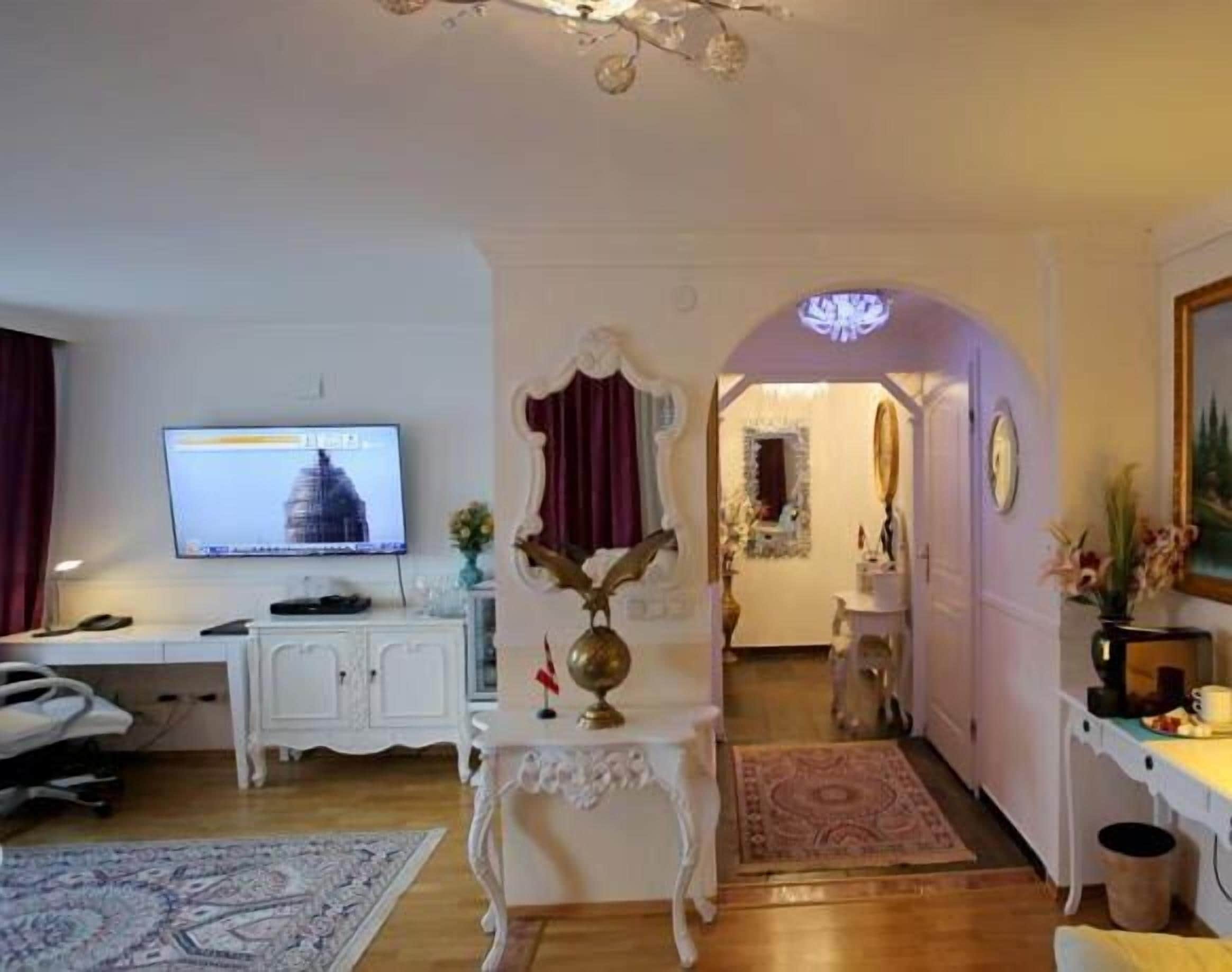 Habitación de hotel con televisión, escritorio con computadora, silla, globo decorativo y alfombra.