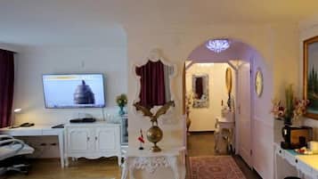 Habitación de hotel con televisión, escritorio con computadora, silla, globo decorativo y alfombra.