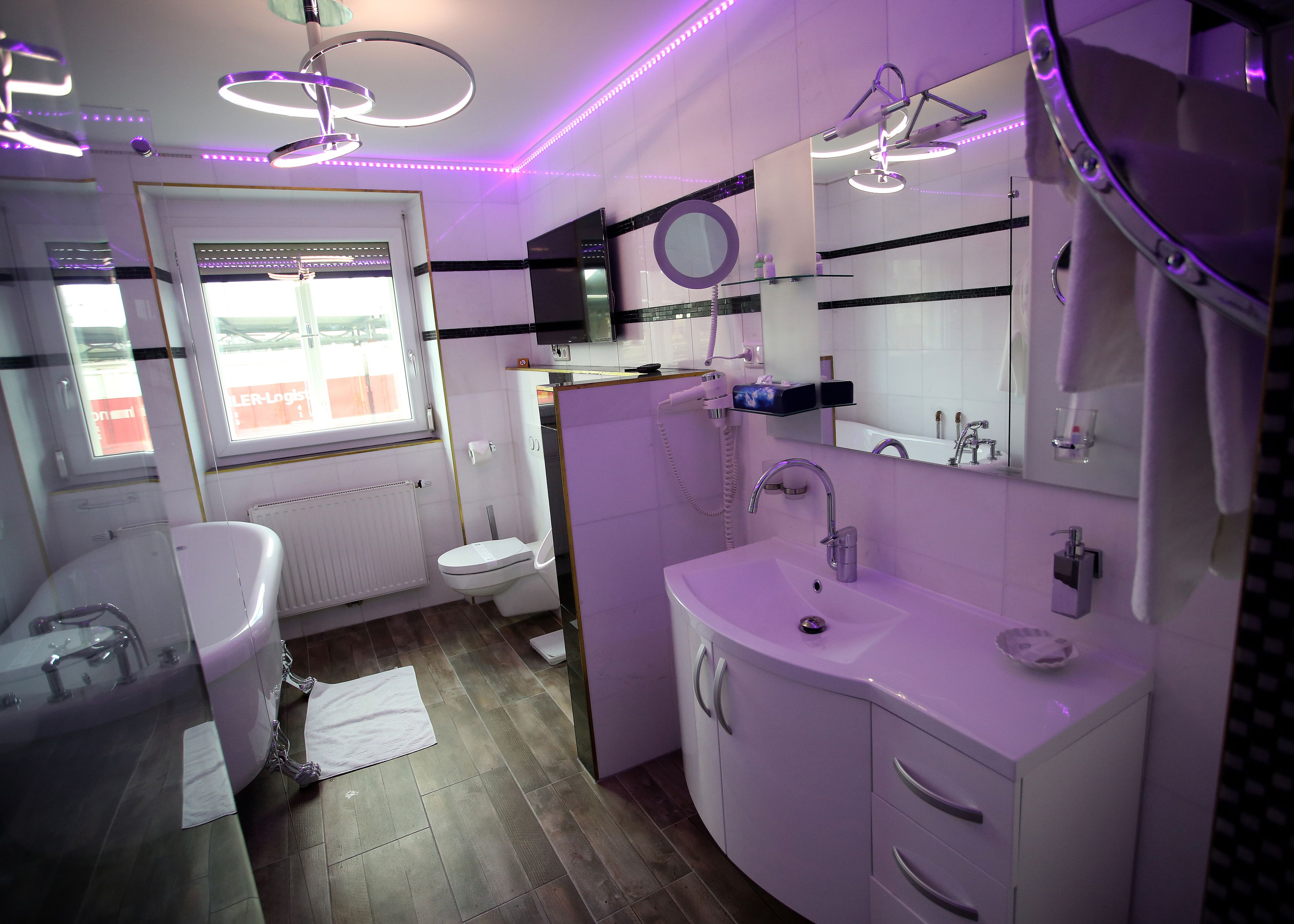 Et moderne badeværelse med toilet, vask og spejl. Der er et vindue med udsigt.