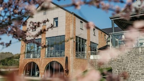 Een modern gebouw met grote ramen, een gevel van baksteen en steen, en een gebogen entree.