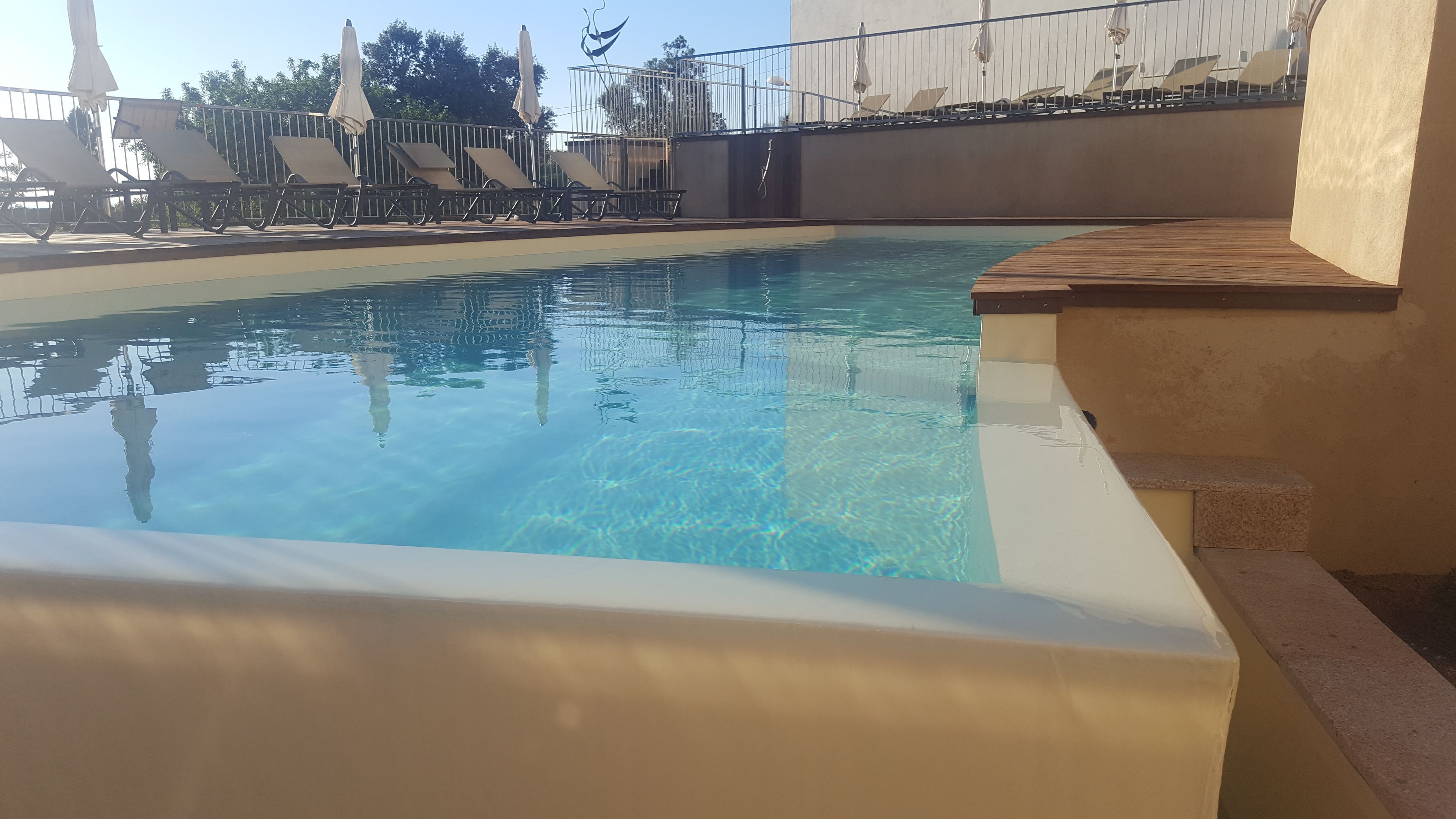 seasonal outdoor pool, an infinity pool, pool umbrellas, pool loungers