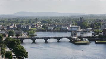 A river with a stone bridge, buildings, and a church with a tower.