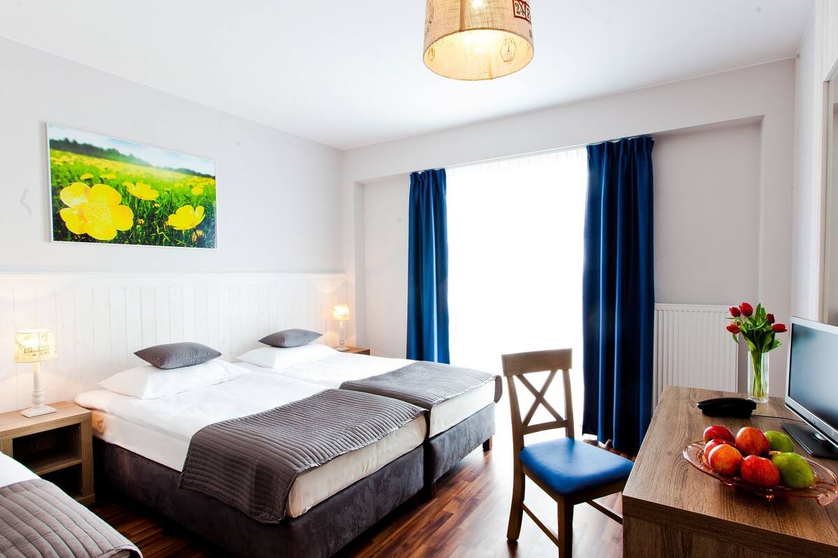 Een hotelkamer met een bed, een bureau met een bloevas, een stoel en een bloemen schilderij aan de muur.