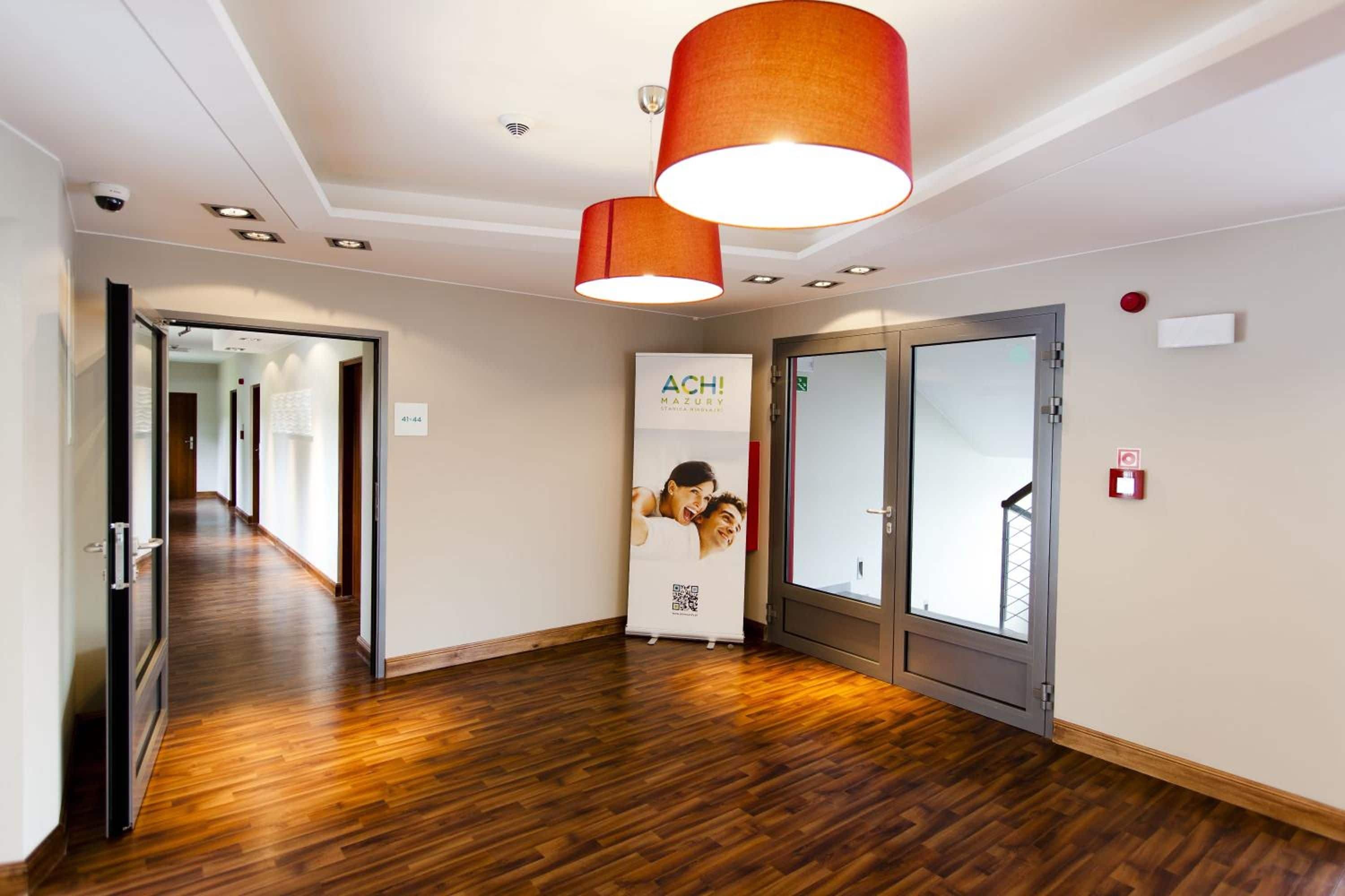 A hotel corridor with wooden flooring, a reception area with a banner, and a door with a glass panel.