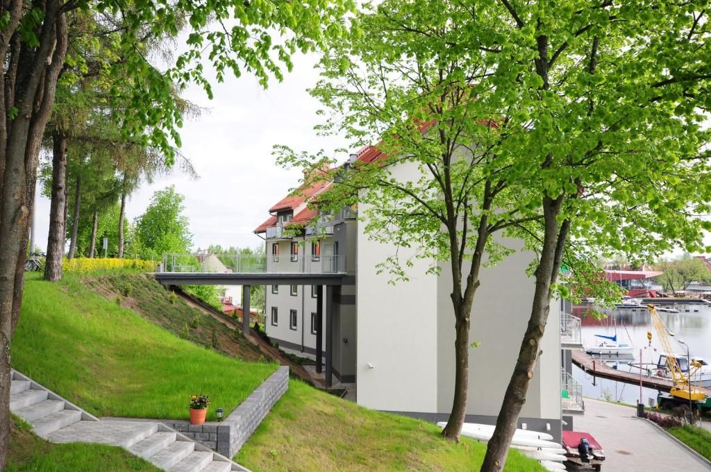 A modern building with a sloped roof, a staircase leading up to a balcony, and a view of a body of water with boats.