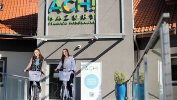 A building with a sign reading 'ACH! MAZURY STANICA NIKOLA' and two individuals riding bicycles.
