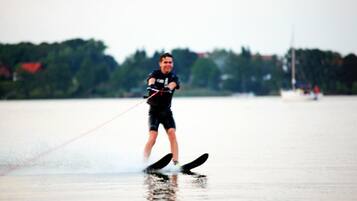 A person wakeboarding on a body of water with a blurred background of trees and buildings.