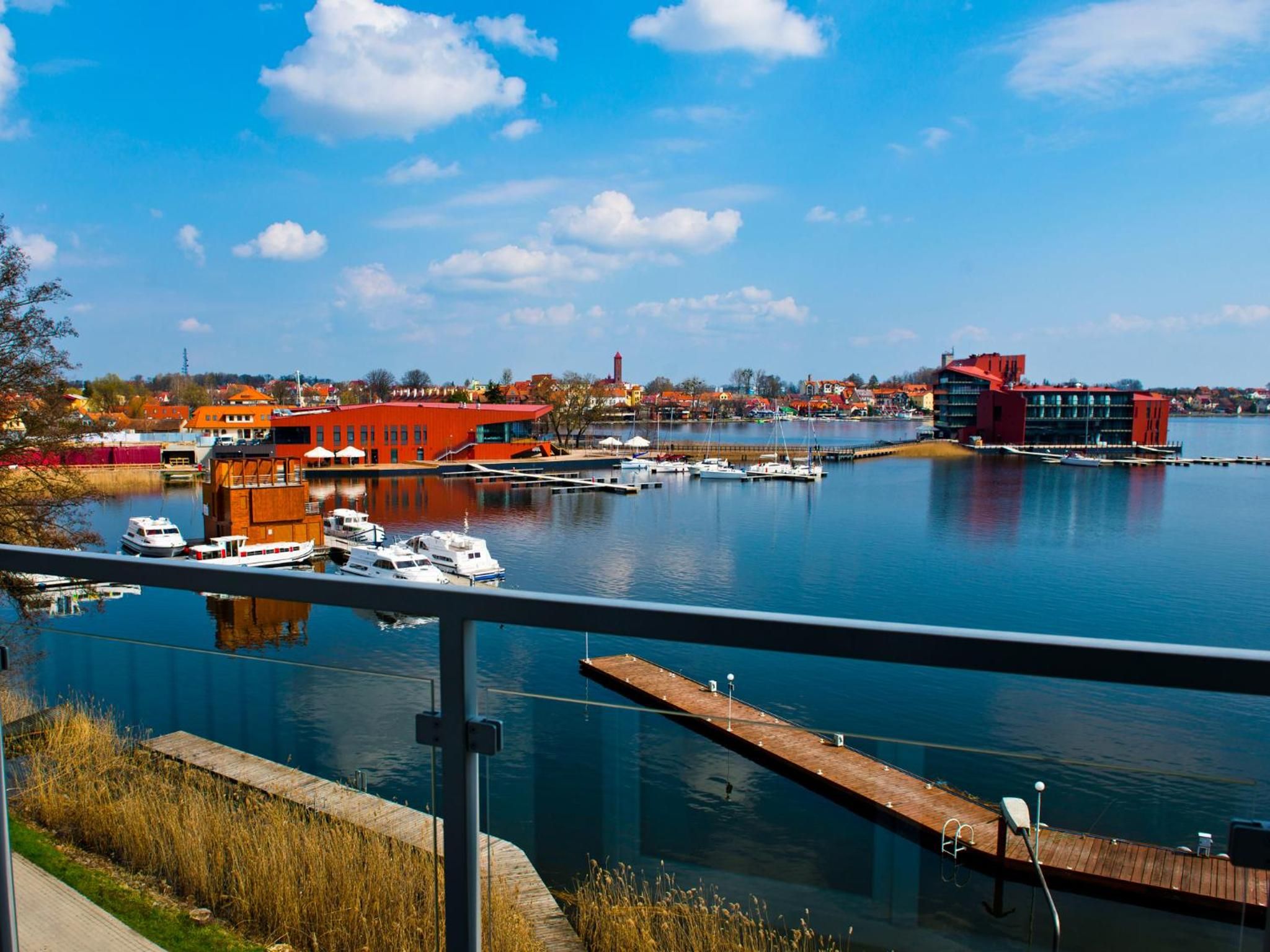 Een jachthaven met aangemeerde boten, een rood gebouw en een helderblauwe lucht.