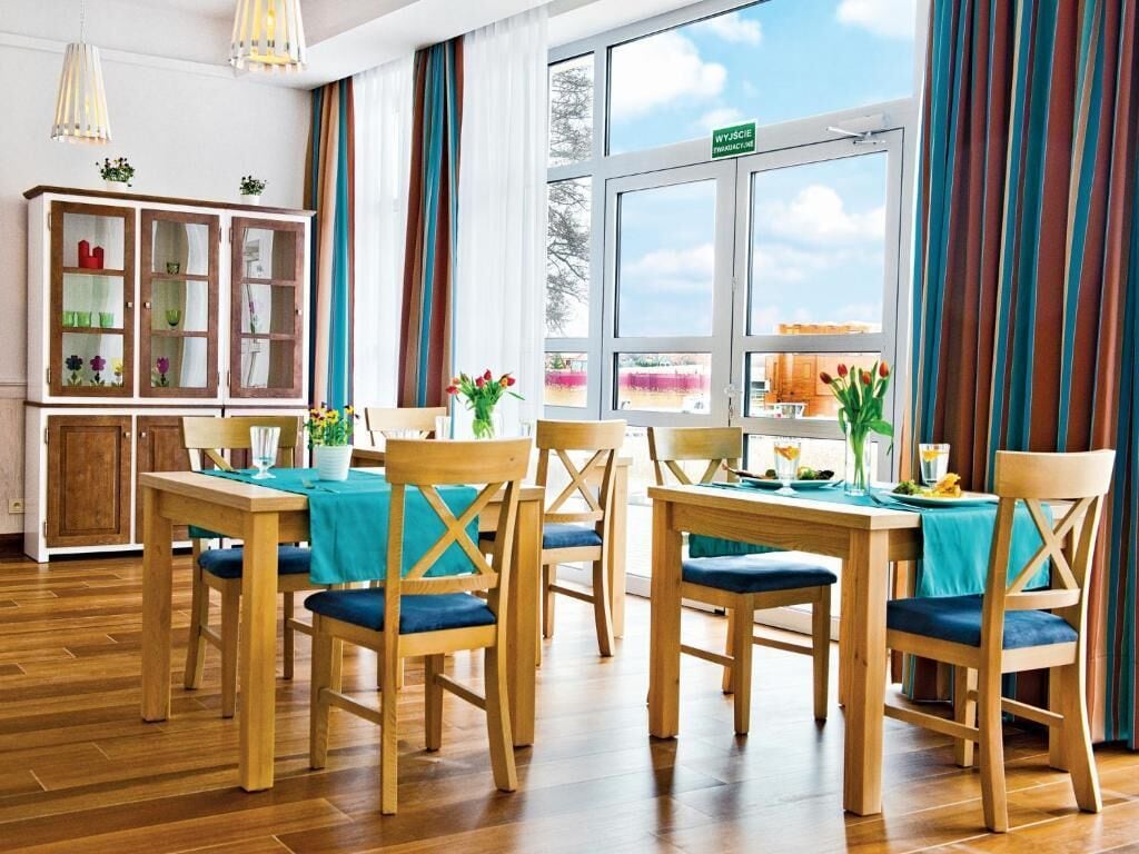 A dining area with wooden furniture, a cabinet with glass doors, and a view through a window.