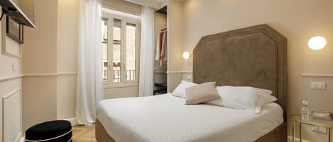 A neatly arranged bedroom with a large bed, a bedside table, and a window with curtains.