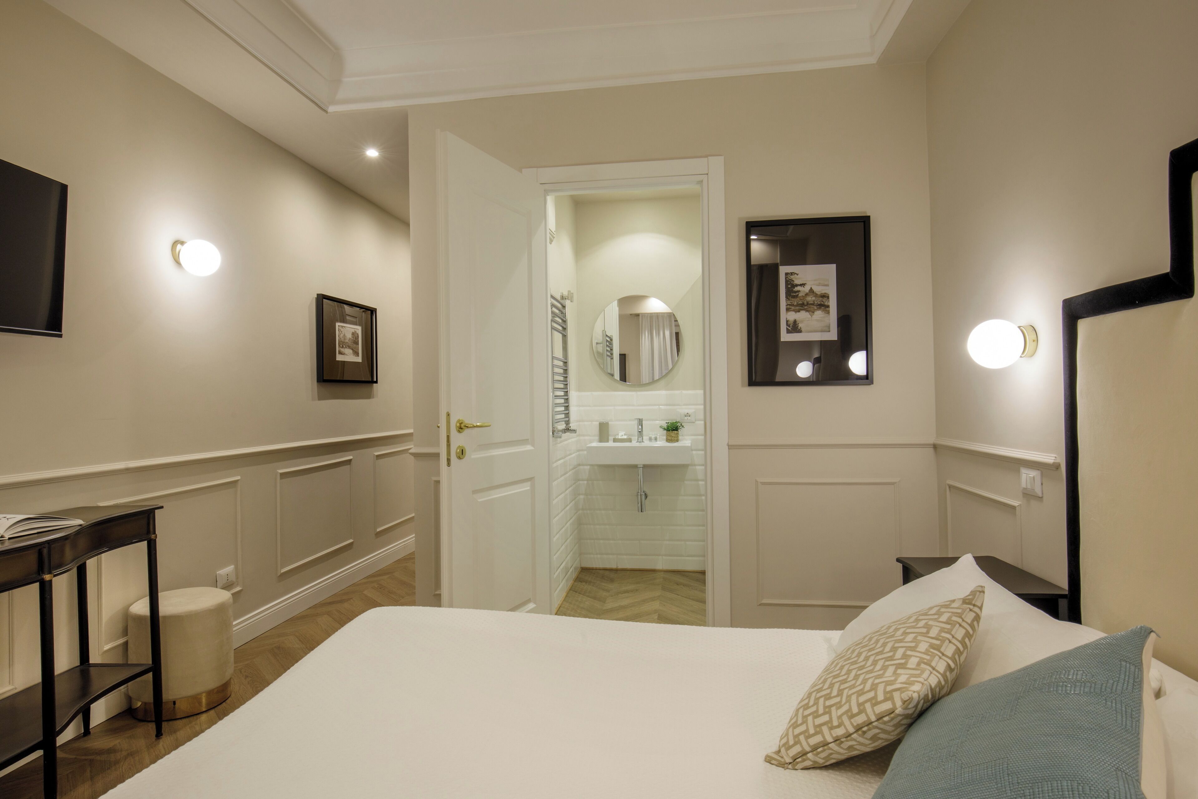 A hotel room with a bed, bedside table, lamp, and a view into the bathroom.