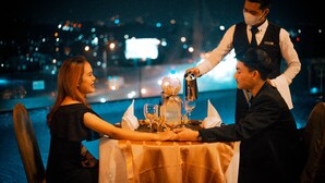 A table set for two with a waiter serving a drink. - Grandia Hotel (Bandung)
