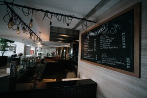 A coffee shop interior with a chalkboard menu listing various drinks and their prices.